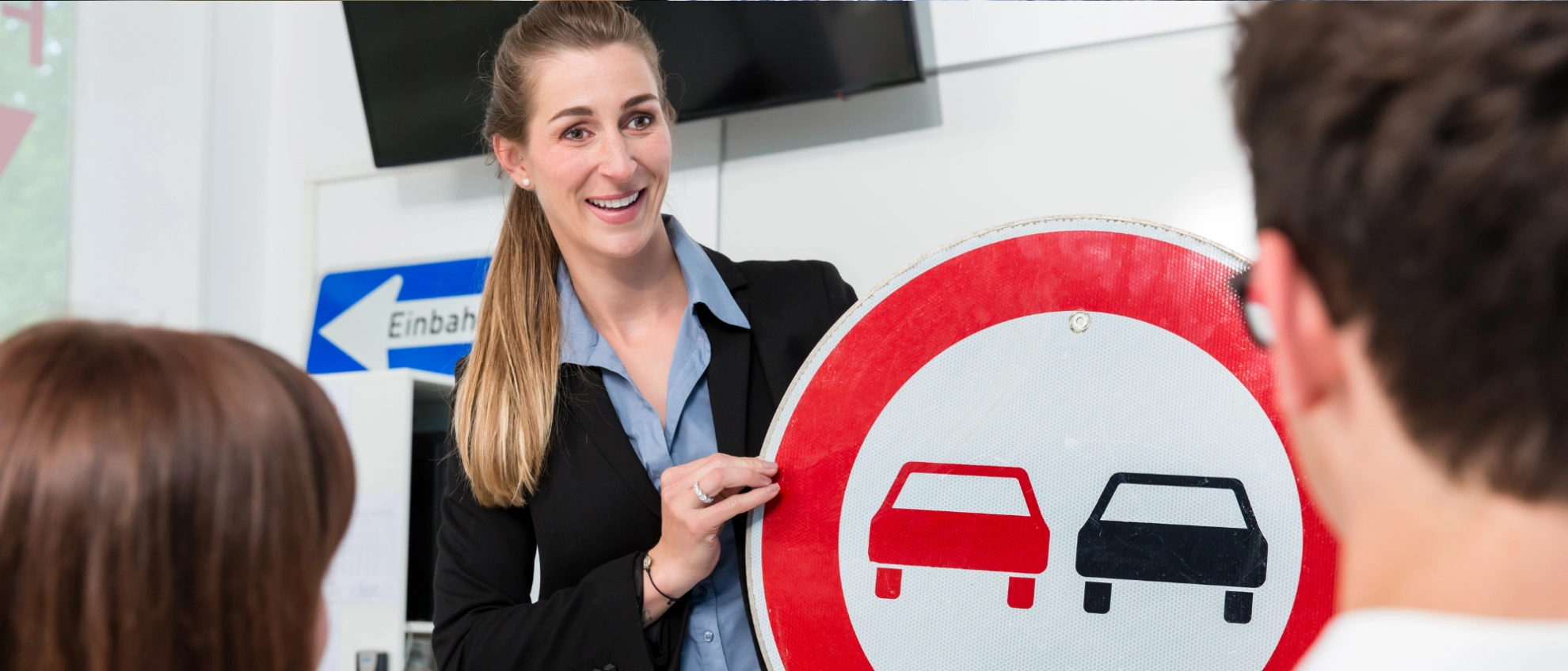 Verkehrsschilder lernen in der Theorie Fahrlehrerin erklärt einer Gruppe ein Überholverbotsschild im theoretischen Unterrichtsraum