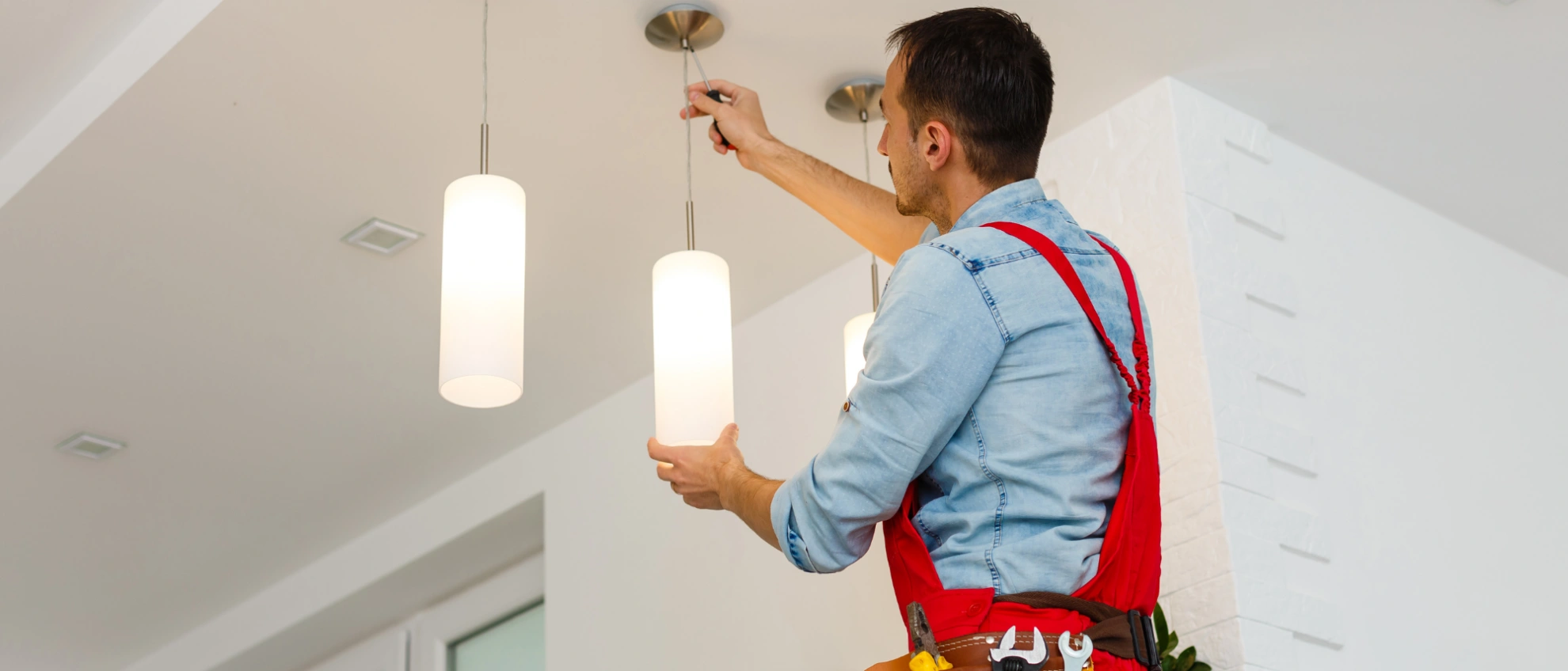 Deckenleuchte montieren Elektriker montiert eine Deckenlampe in einem Wohnraum mit weißer Wand