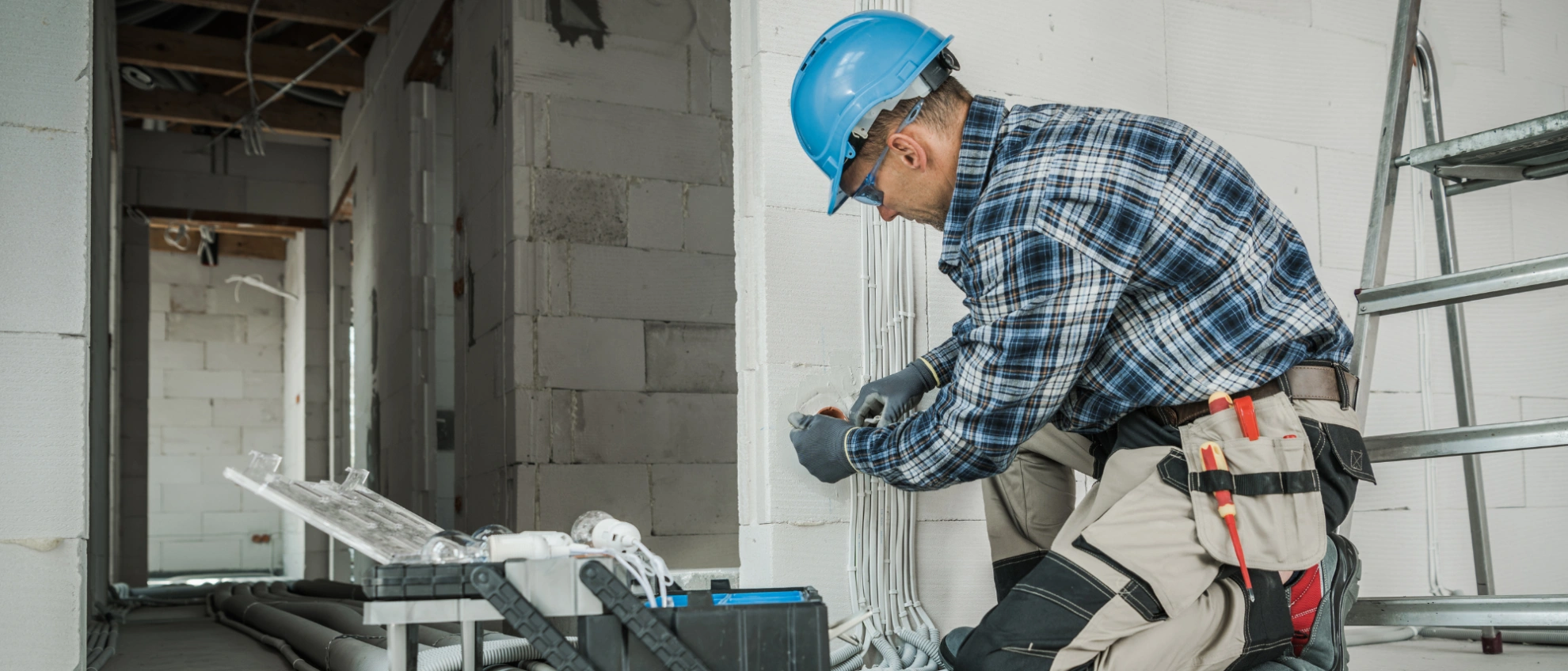 Leitungsverlegung im Rohbau Elektriker in Schutzkleidung verlegt Kabel an der Wand eines Rohbaus