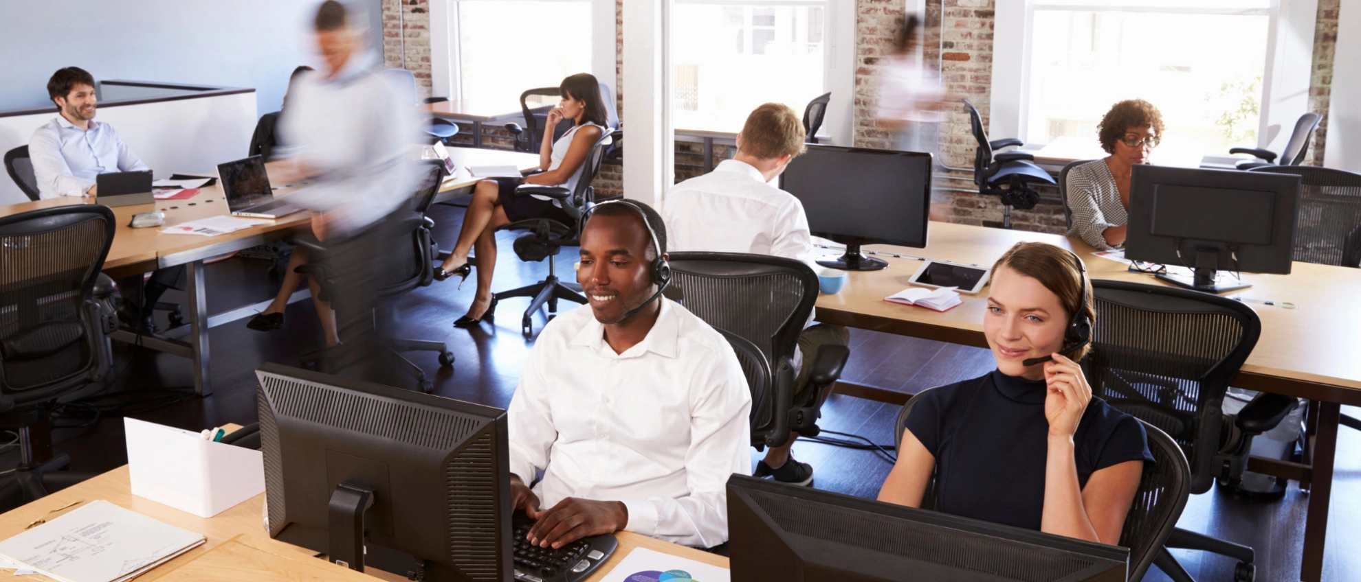 Kundenservice im Großraumbüro Callcenter-Mitarbeiterinnen mit Headset arbeiten konzentriert an ihren Plätzen