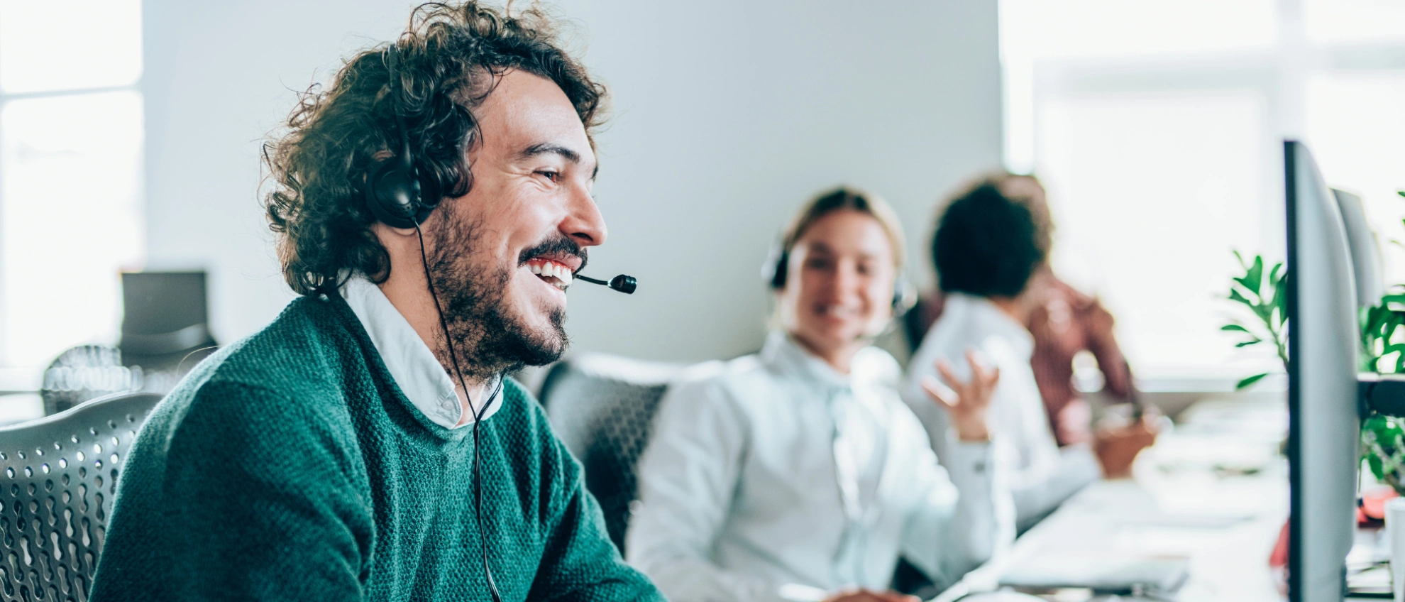 Freundlicher Support im Callcenter Mann mit Headset lächelt im Callcenter während des Kundengesprächs
