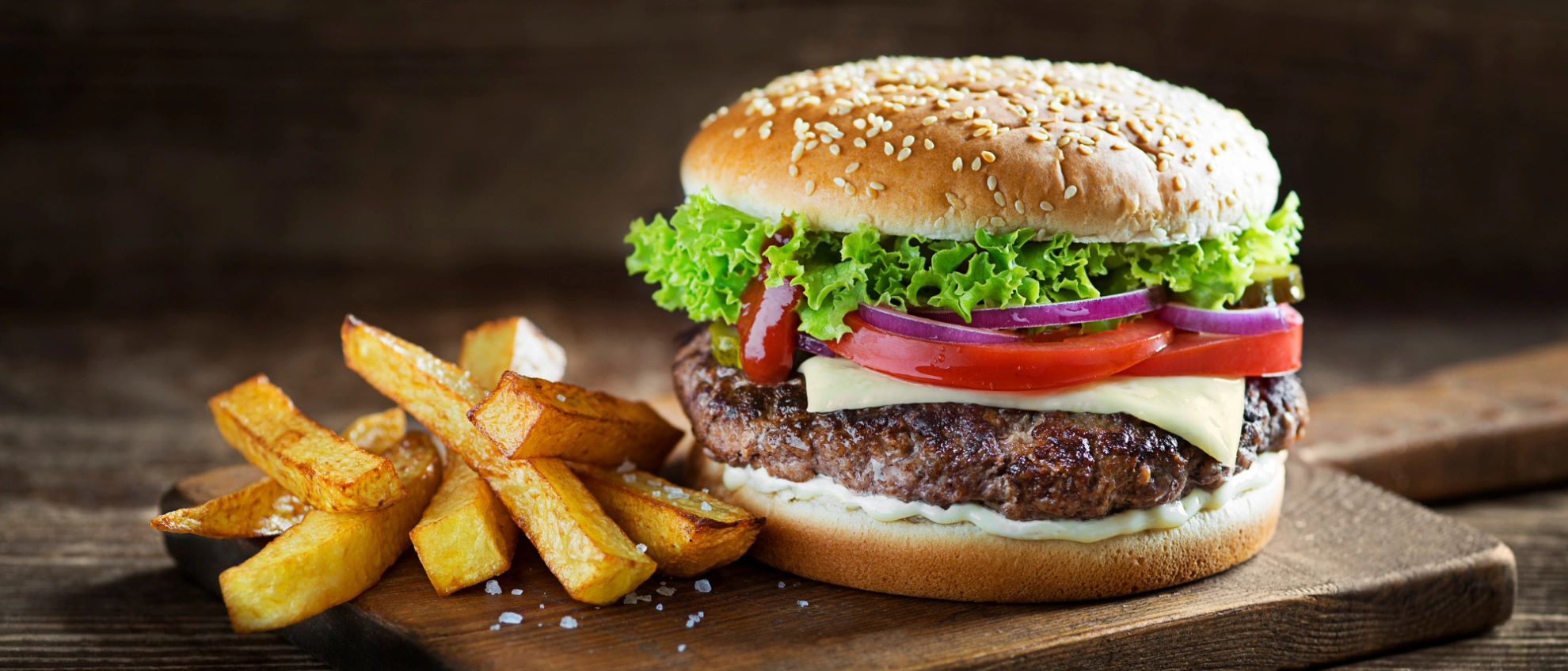 Frischer Burger mit Salat und Tomaten Frischer Burger mit Salat, Tomaten und Sesambrötchen auf Holzbrett