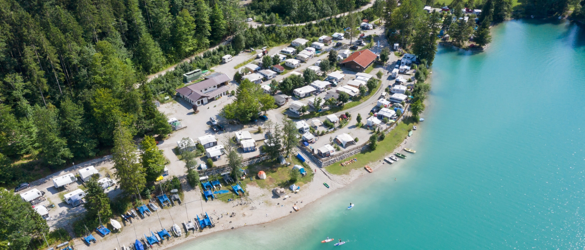 Campingplatz am See Luftaufnahme eines idyllischen Campingplatzes direkt am türkisblauen Seeufer