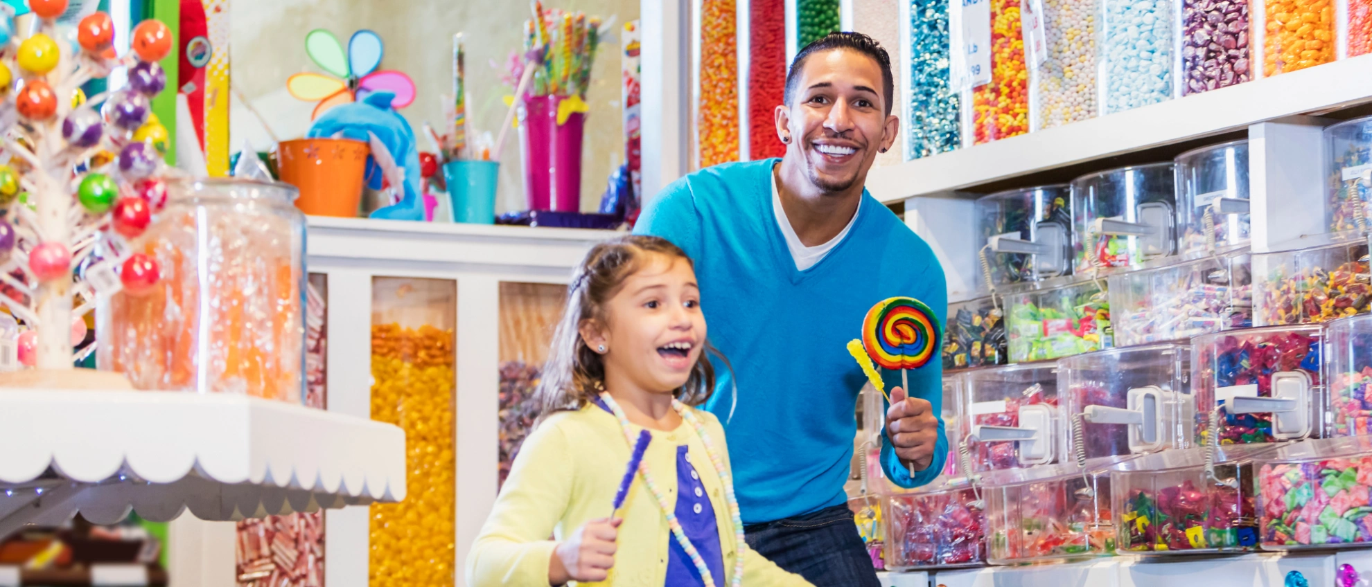 Vater und Tochter stöbern in einem farbenfrohen Laden mit Bastelmaterial und Spielzeug