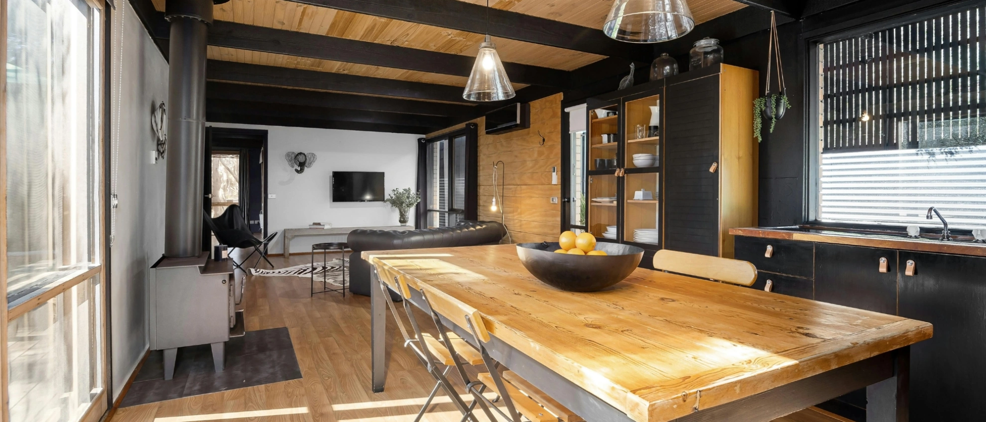 Stilvolles Interieur eines modernen Tiny House Innenansicht eines Tiny Houses mit großem Esstisch und Küche im rustikal-modernen Design