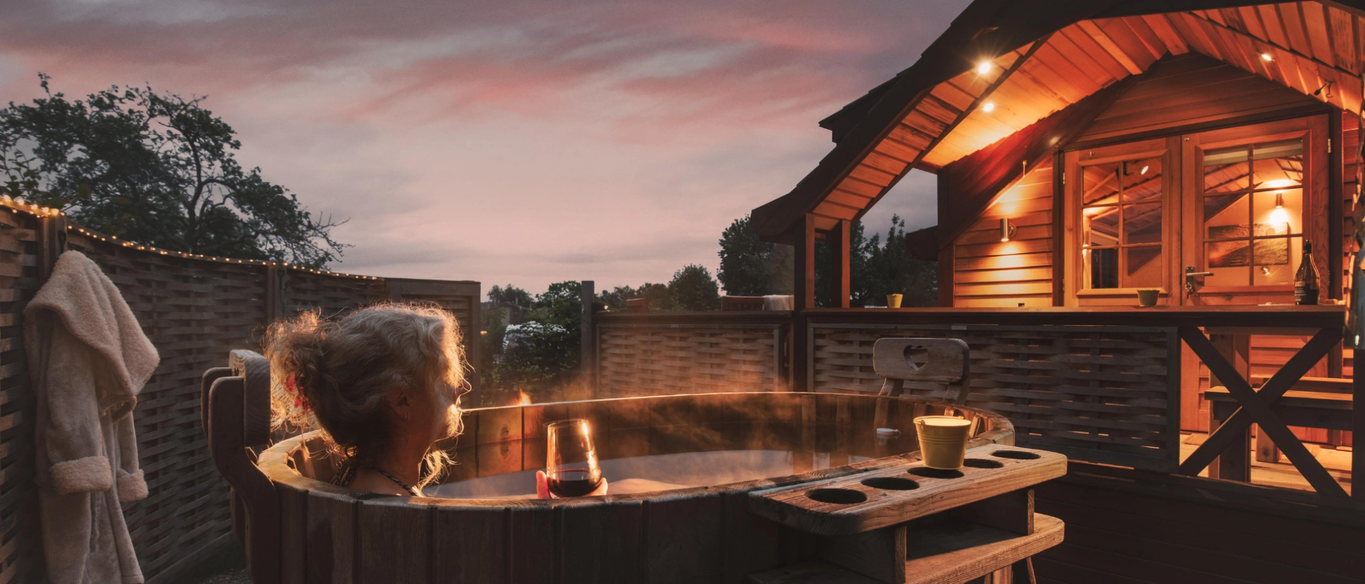 Abendstimmung im Tiny House Dorf mit Wellnessbereich Holzhaus mit Außenwanne bei Sonnenuntergang