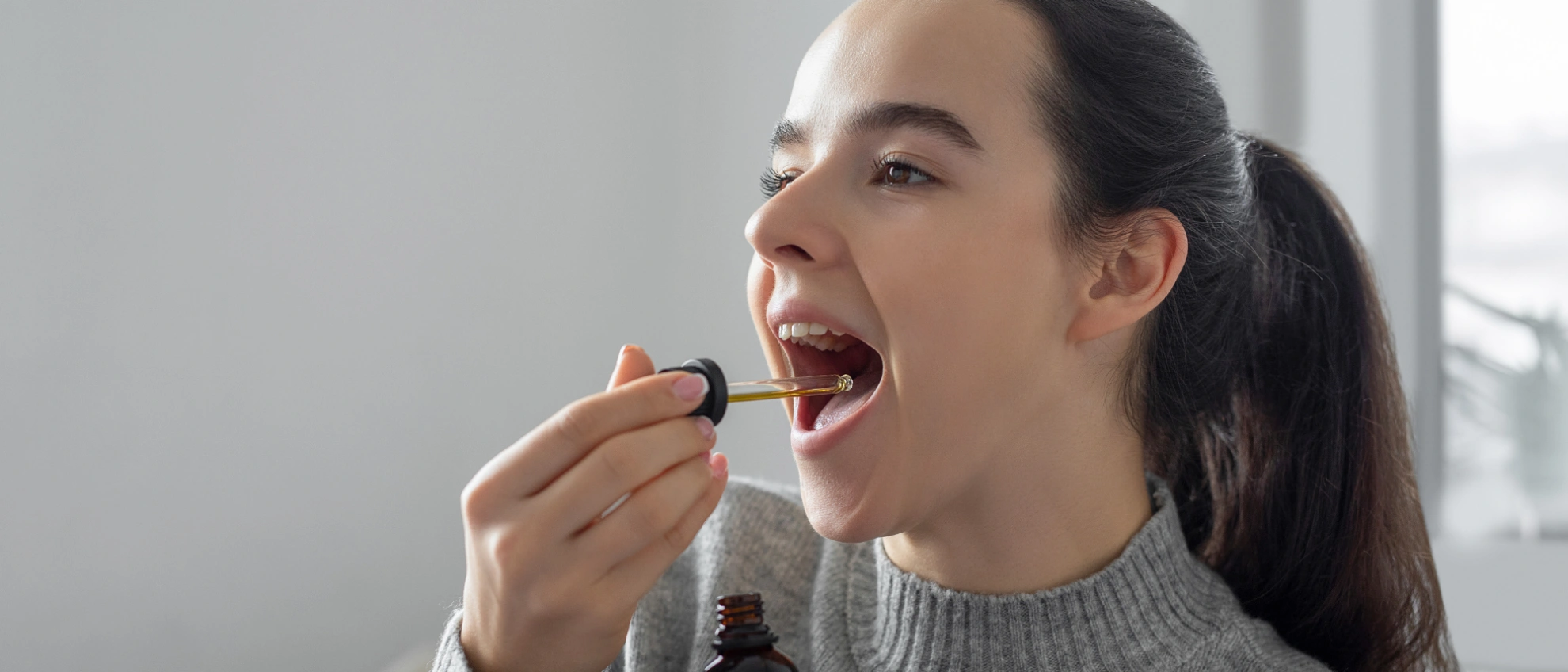 Junge Frau tropft sich CBD-Öl direkt in den Mund