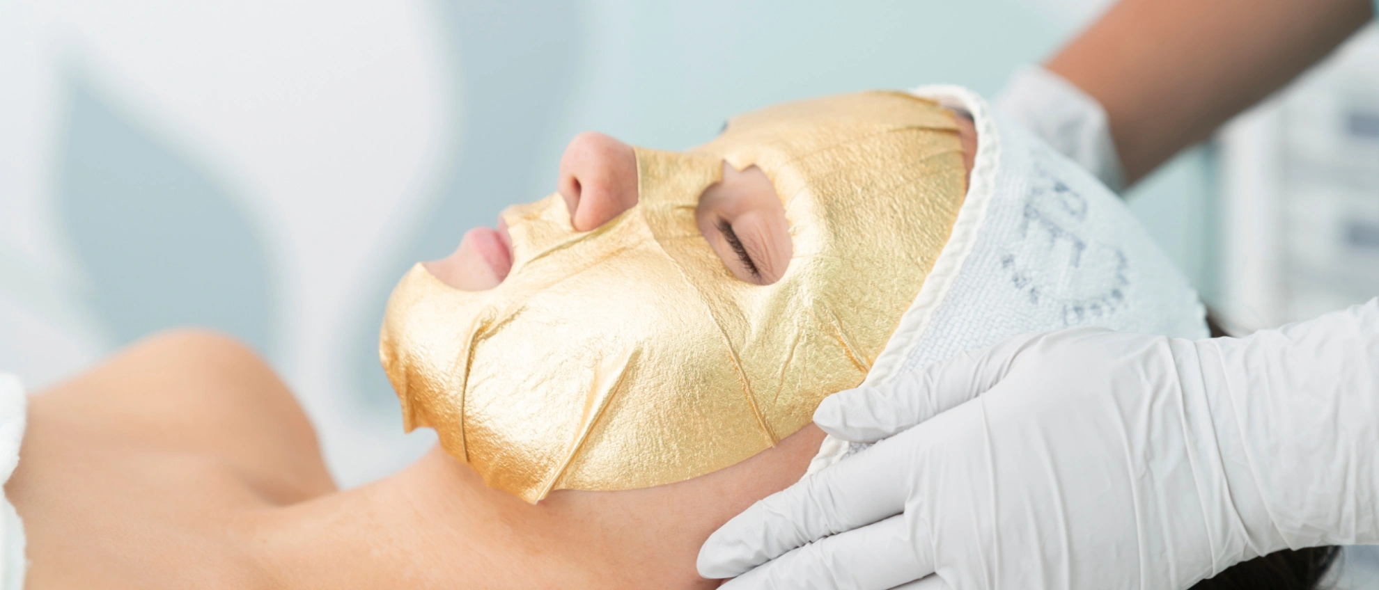 Frau mit goldener Gesichtsmaske während einer professionellen Kosmetikbehandlung