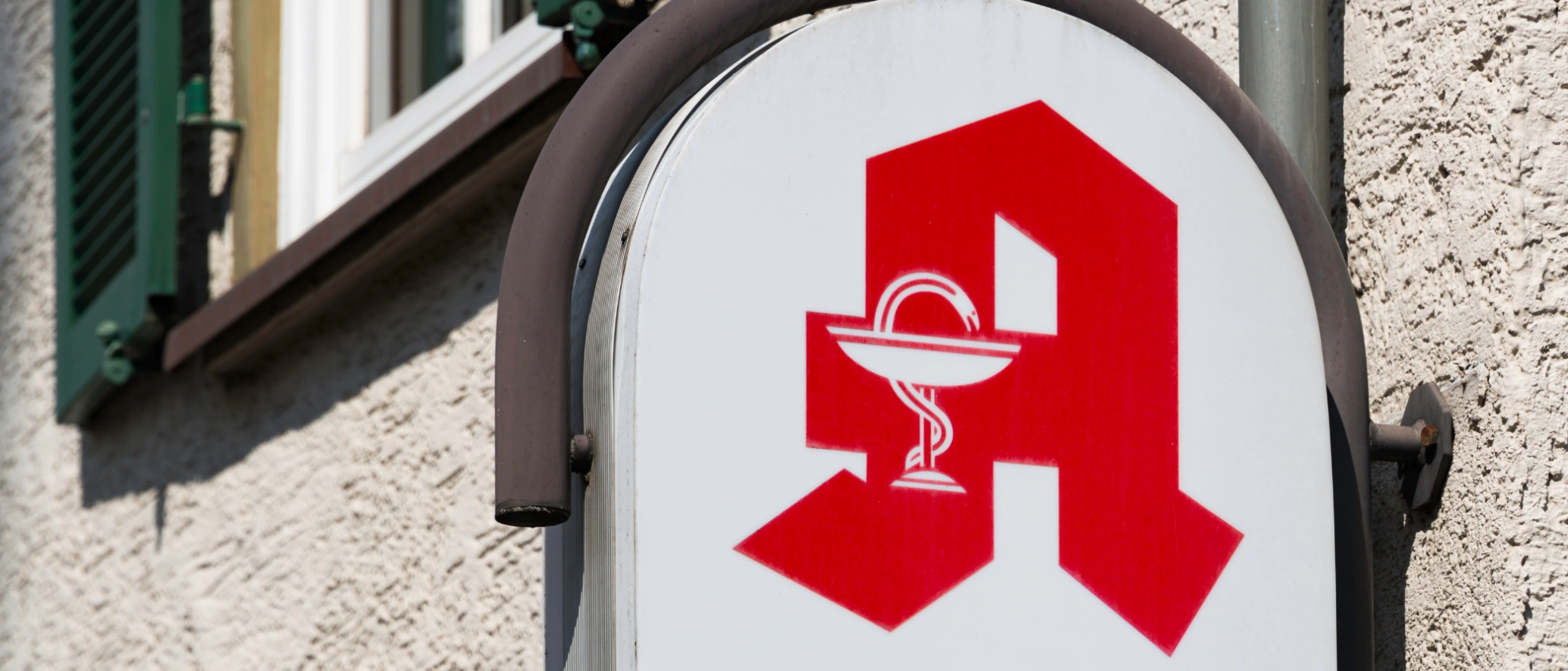 Klassisches Apotheken-A mit Schale und Schlange als Leuchtschild an einer Hauswand