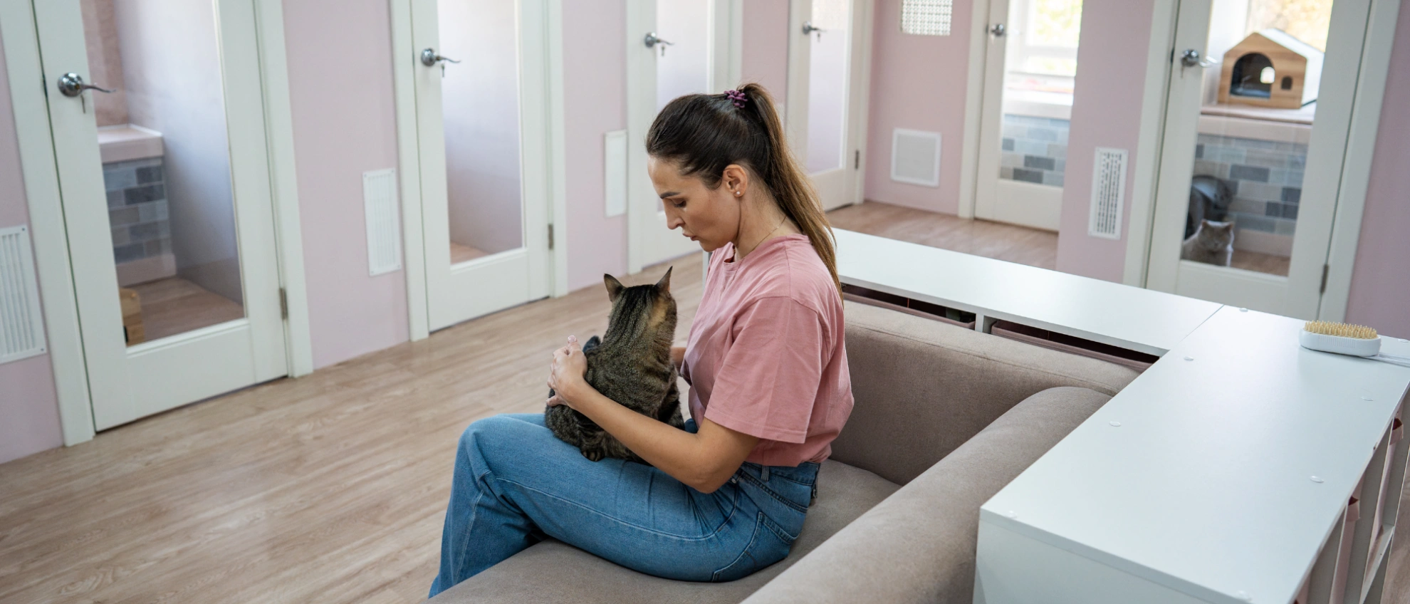Frau sitzt in einer Katzenlounge und hält eine Katze auf dem Schoß