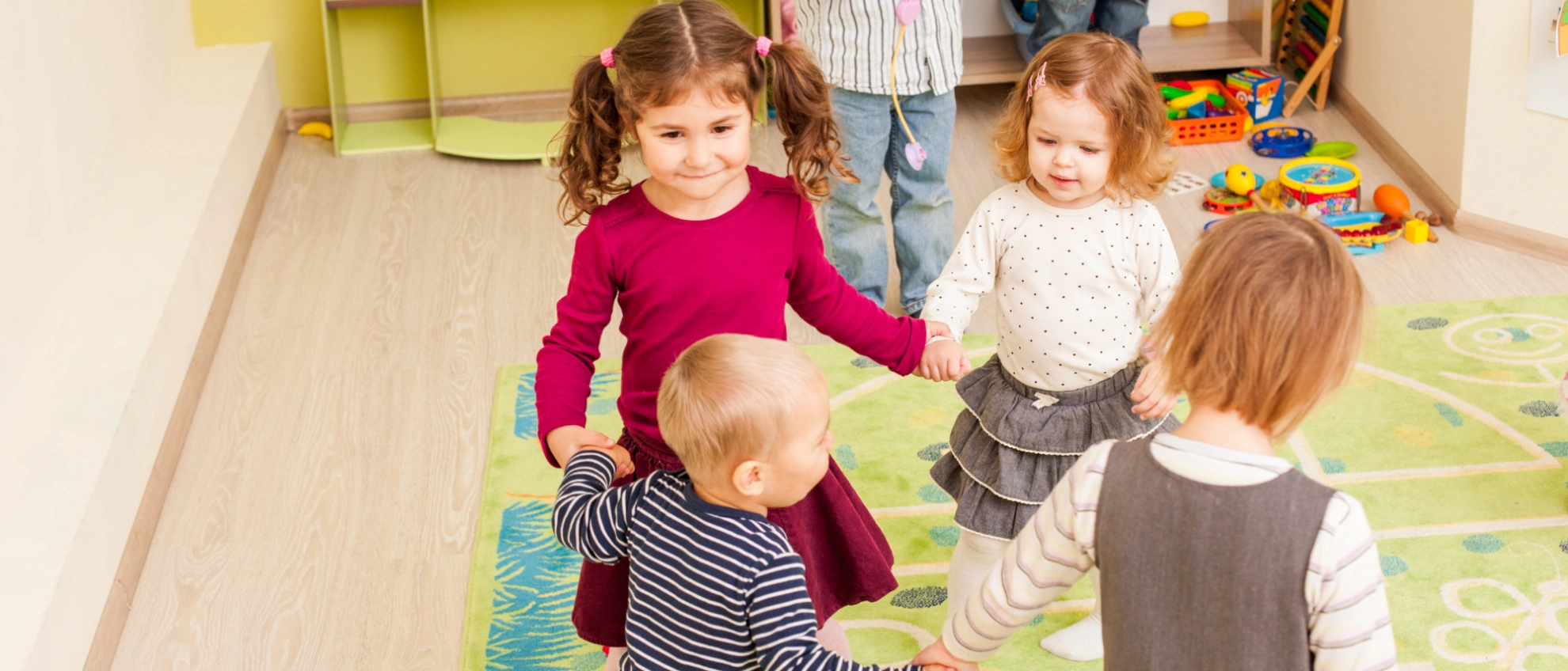 Kleinkinder spielen gemeinsam auf einem weichen Spielteppich im Gruppenraum