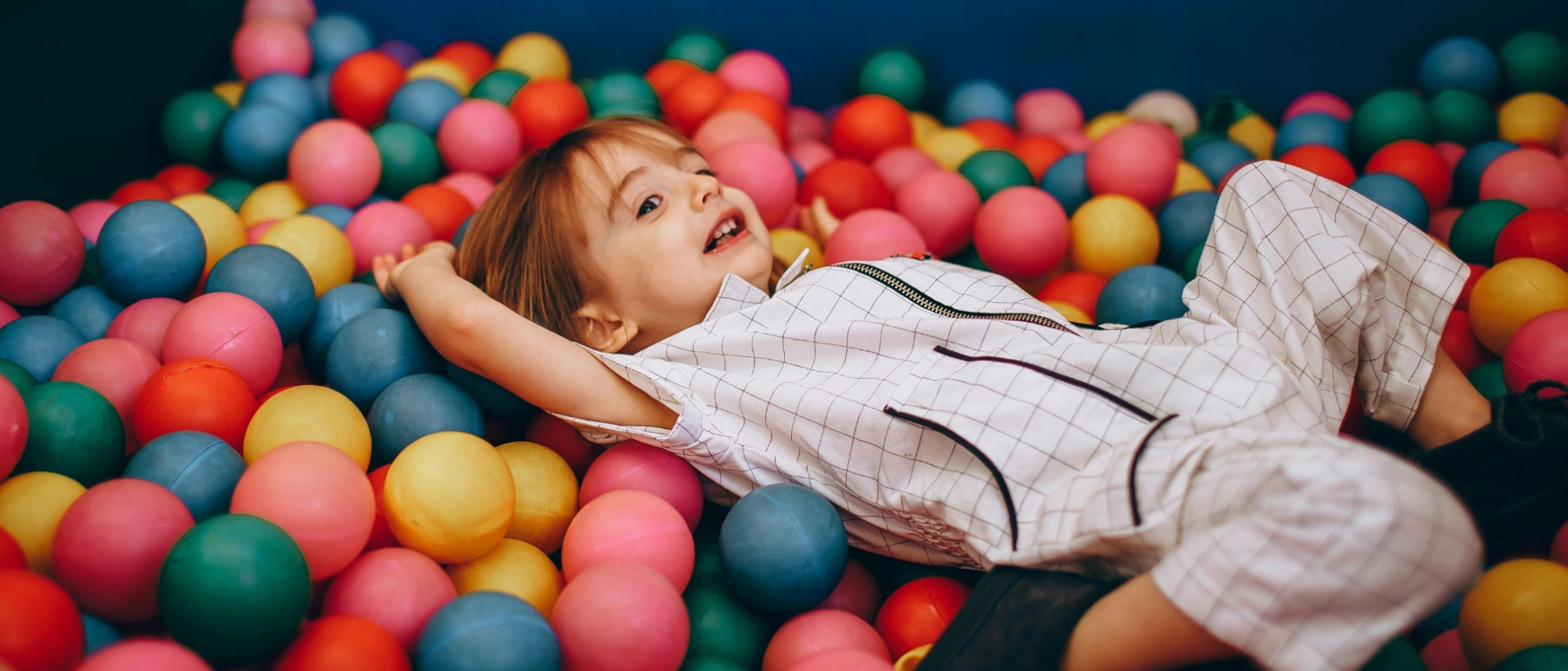 Kinder sitzen an einem Tisch und essen zusammen mit rotem Kindergeschirr
