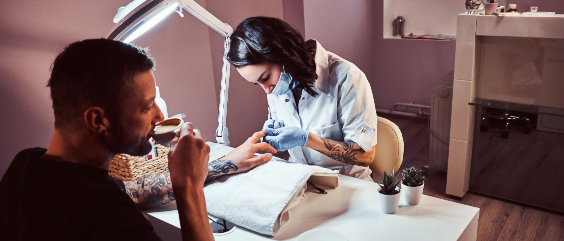 Nageldesignerin behandelt Hände eines Kunden im hell beleuchteten Studio