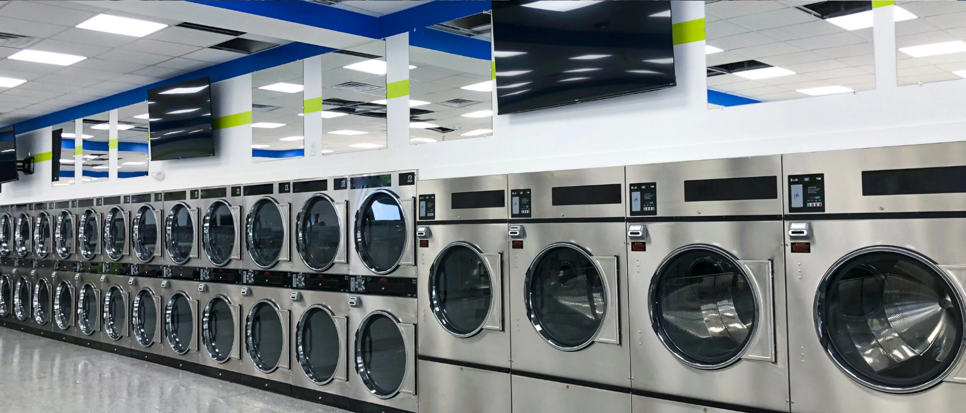 Panoramaaufnahme eines Waschsalons mit vielen silbernen Großwaschmaschinen