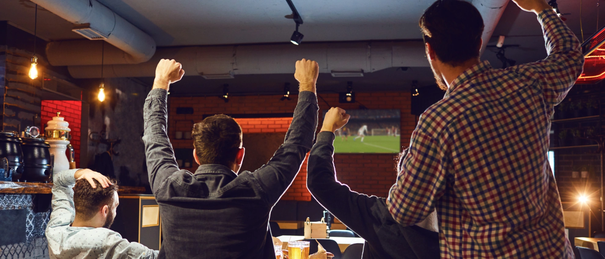 Stimmung beim Public Viewing Gäste in einem Lokal jubeln und feiern mit erhobenen Armen bei einem Sportereignis