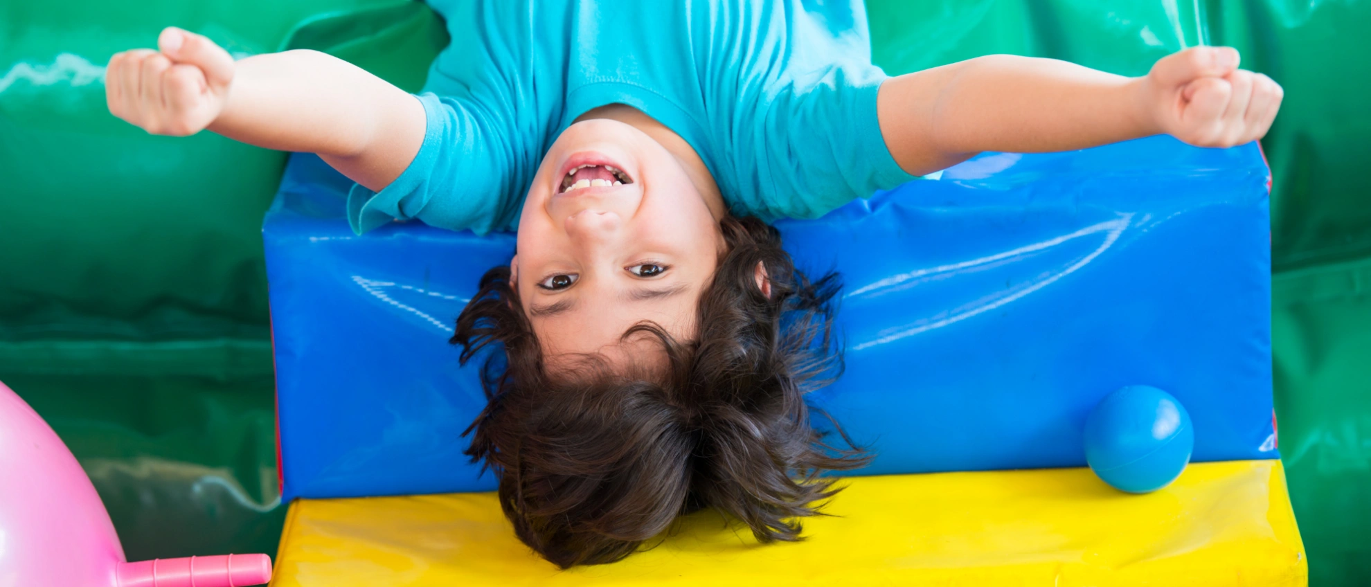 Kind liegt rückwärts auf einer aufblasbaren Matte und lacht in die Kamera