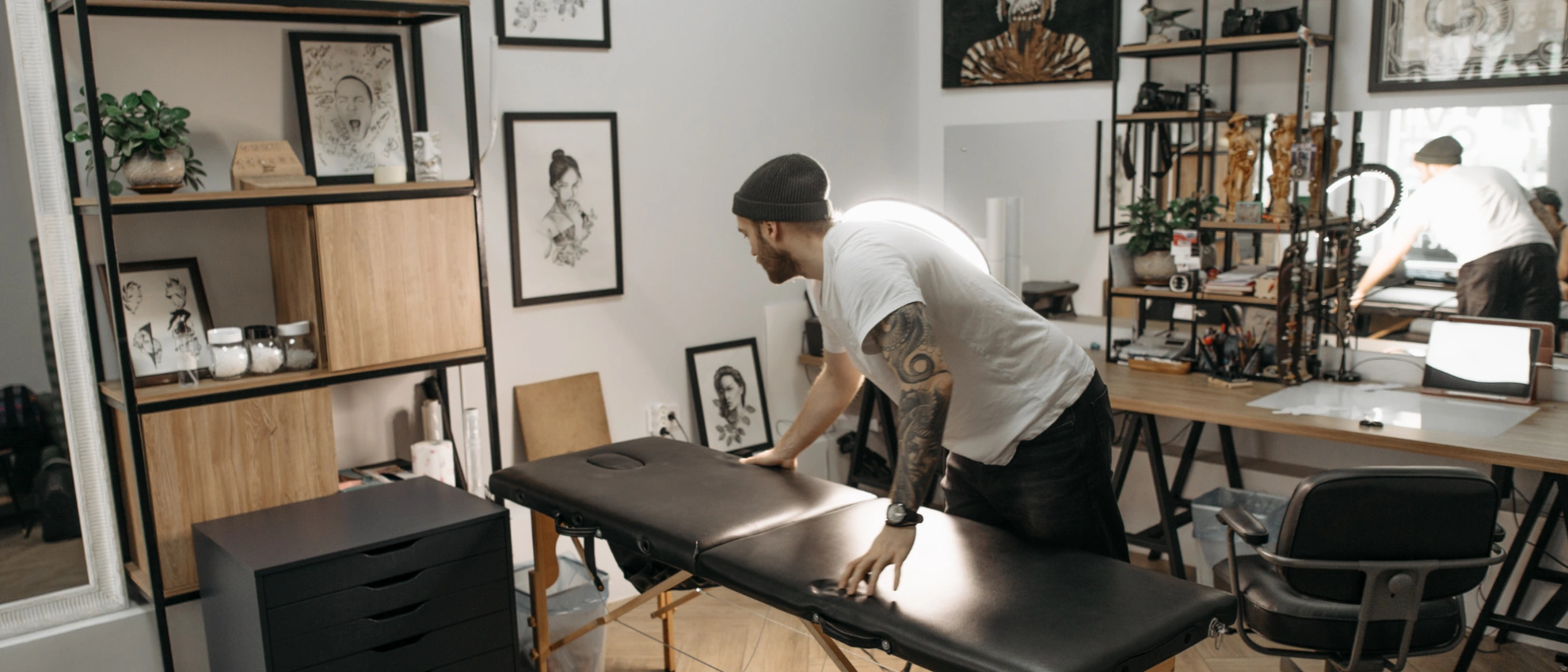orbereitungen im Tattoo-Studio – hygienisch und stilvoll Tätowierer richtet eine Liege im stilvoll eingerichteten Tattoo-Studio her