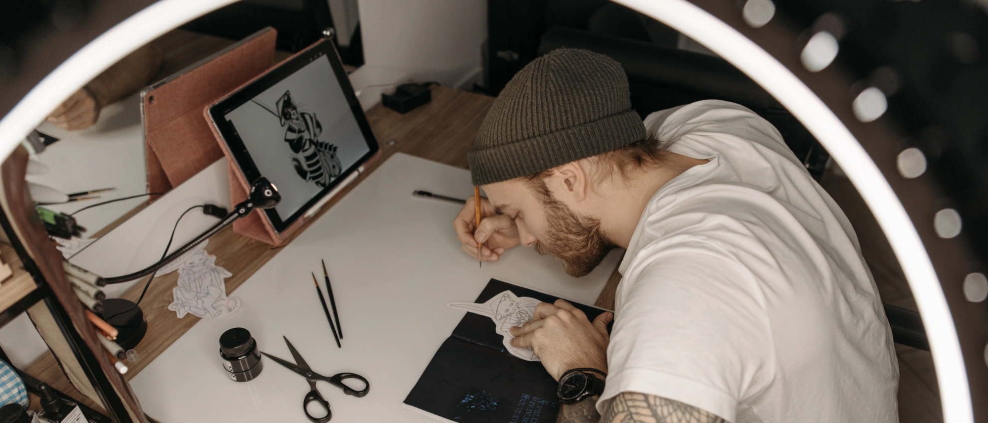 Tattoo-Design am Zeichentisch – individuelle Vorlagen für einzigartige Kunst Tätowierer zeichnet ein neues Tattoo-Motiv an einem hell beleuchteten Arbeitstisch