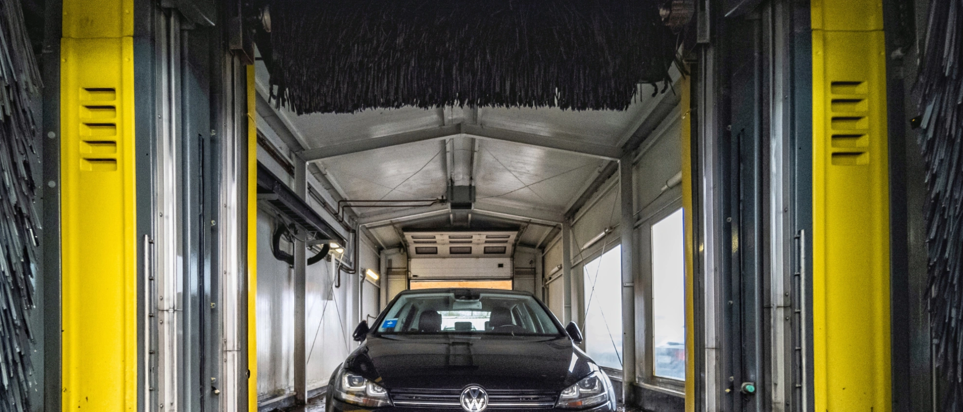 Einfahrt in die Waschstraße – bereit für die Reinigung Fahrzeug fährt in eine gelbe automatische Autowaschanlage ein