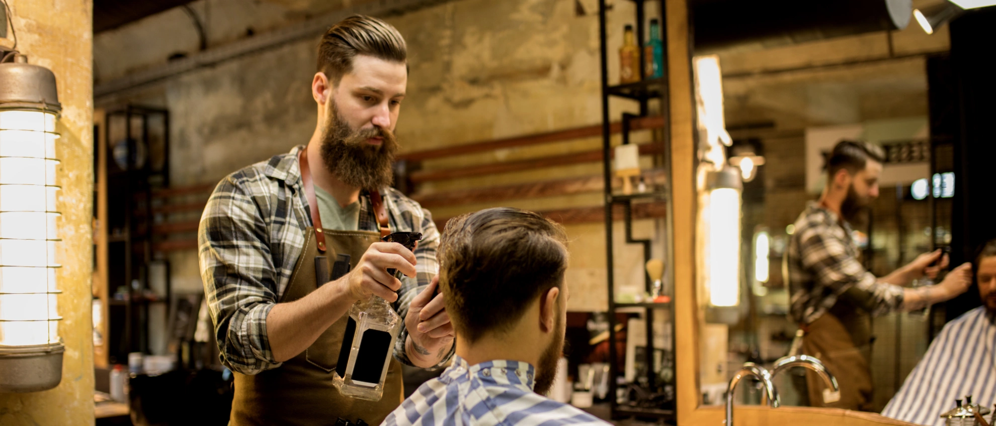 Bärtiger Friseur schneidet einem Kunden im holzvertäfelten Barbershop die Haare