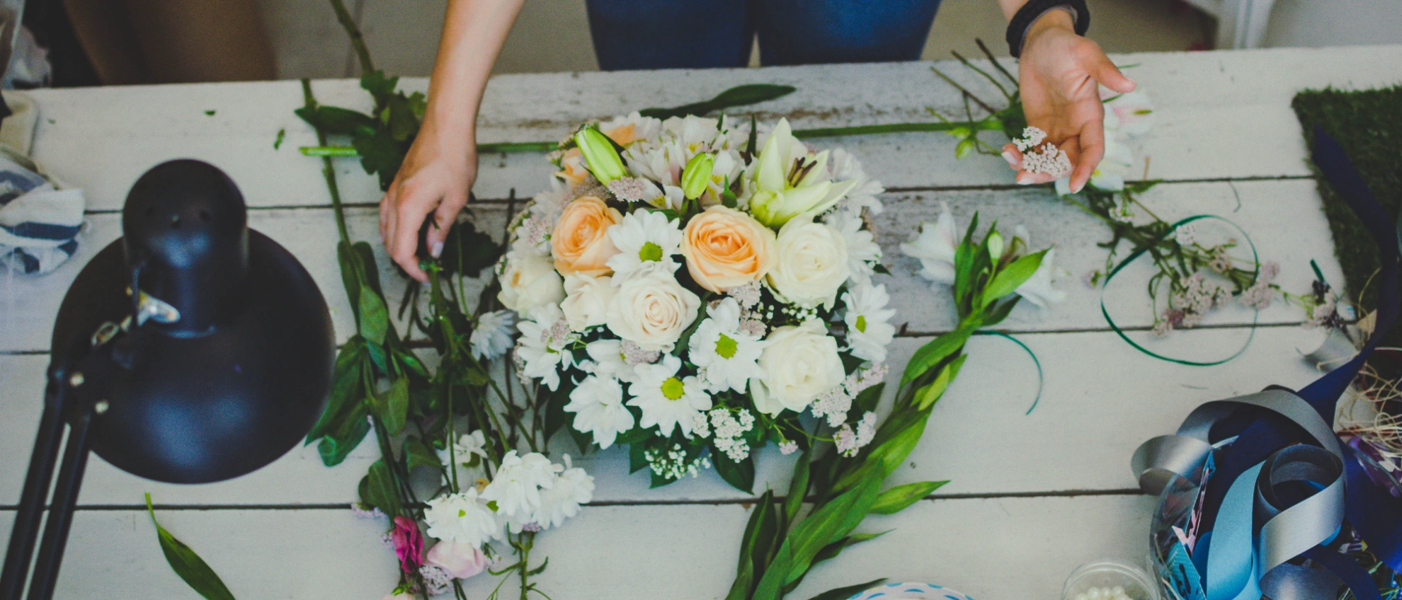 Floristin arrangiert Blumen auf einem Tisch, frisches Bouquet mit weißen und gelben Rosen im Mittelpunkt