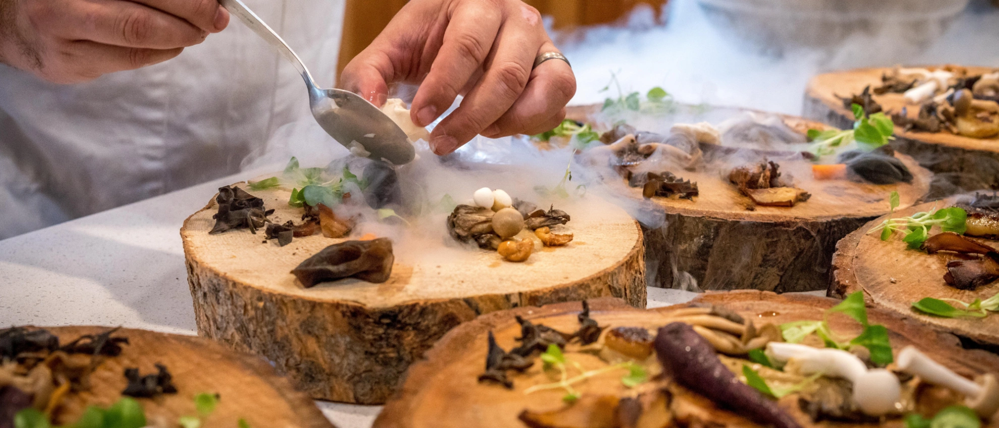 Anrichten eines aufwendigen Tellers in der Restaurantküche Hände eines Kochs beim Garnieren eines Gourmettellers mit Rauch- oder Nebeleffekt