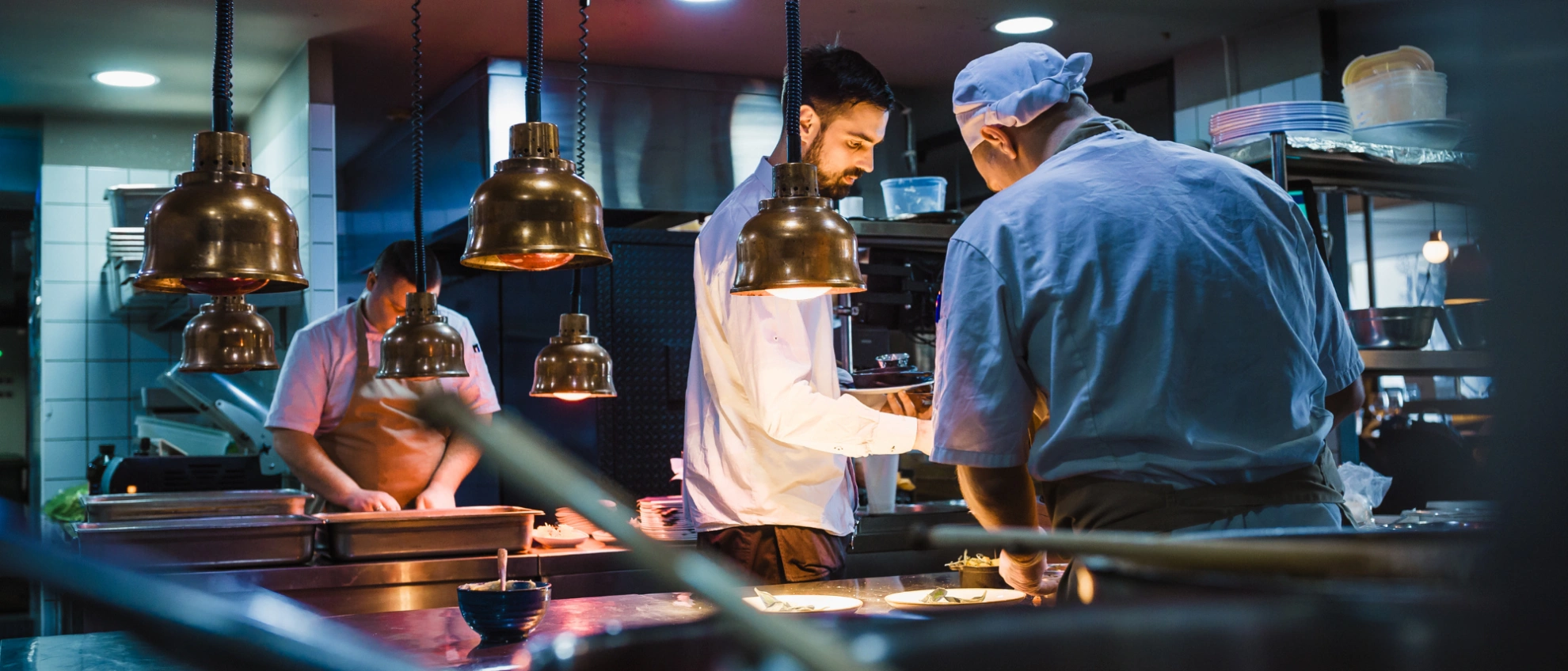 Blick in die offene Küche eines modernen Restaurants Koch arbeitet unter Wärmelampen in einer offenen, professionellen Restaurantküche