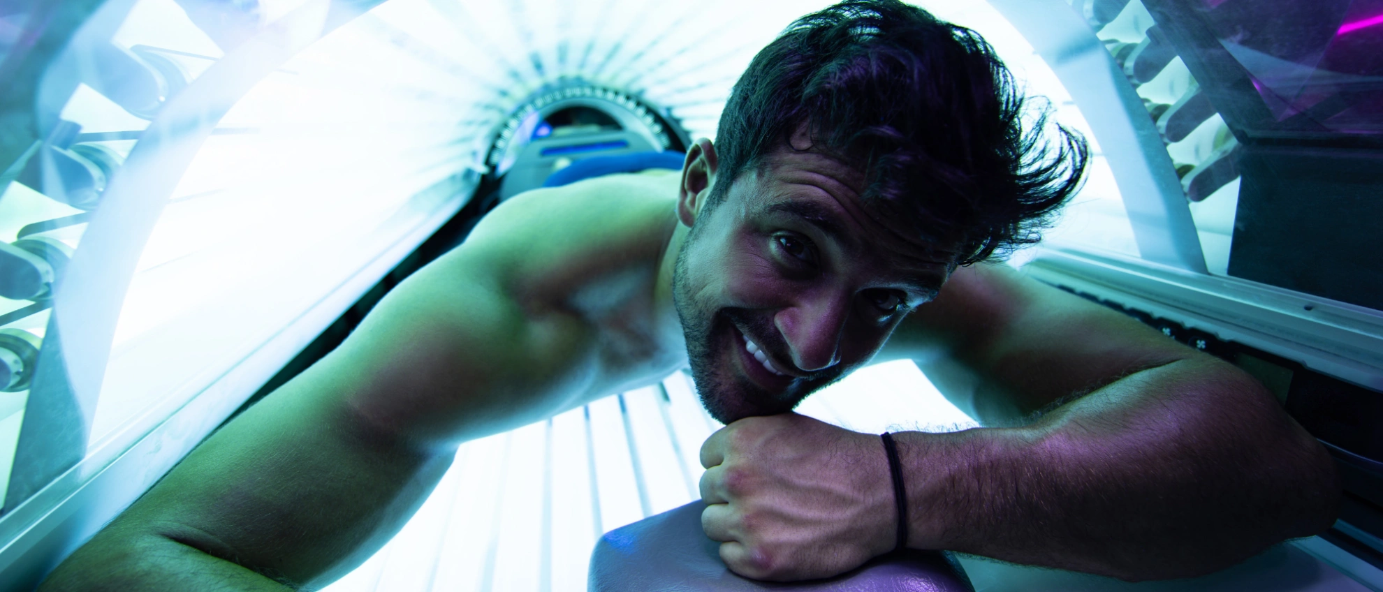 Mann liegt im Solarium und schaut lächelnd zur Kamera