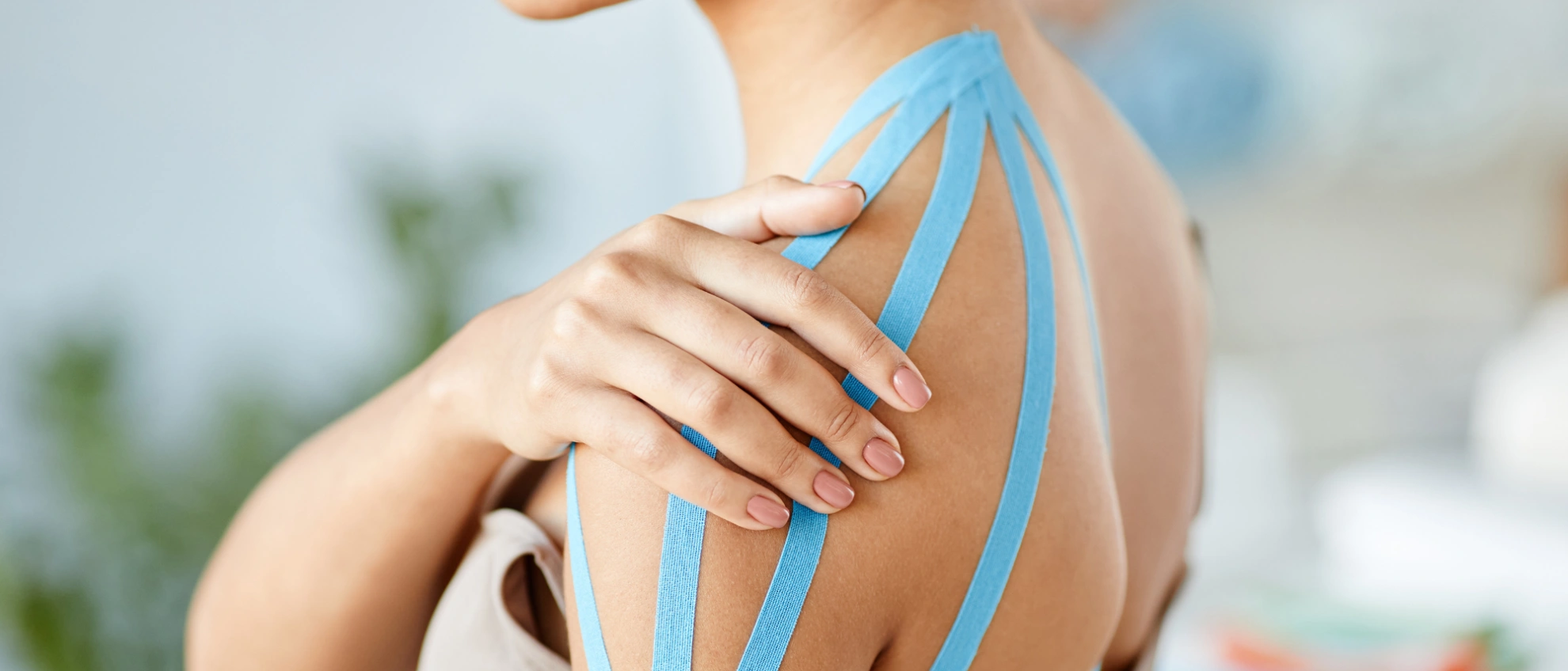 Schulter mit aufgeklebten blauen Kinesiotapes zur Stabilisierung