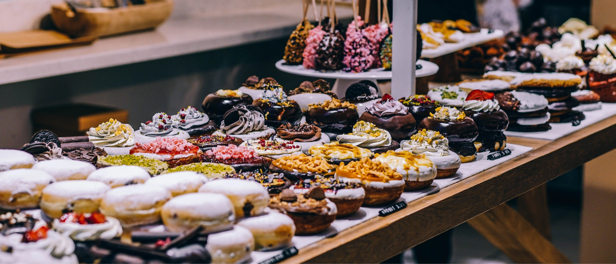 Kreative Donuts und Süßgebäck – Vielfalt in der Konditorei-Theke Große Auswahl an dekorierten Donuts und Süßgebäck auf einer Verkaufstheke in einer Konditorei